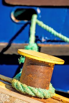 bollard with mooring line and blue ship hull
