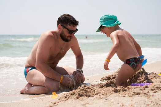 Father son together summer vacation playing sand sea beach Dad kid enjoyment togetherness weekend activity.
