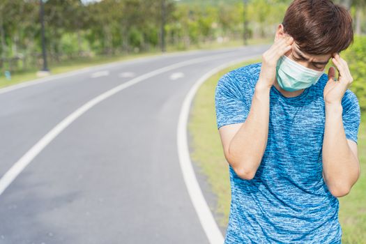 Young male wearing medical mask have headache while workout at t
