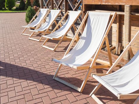 Deckchairs are at cafe's verandah. Visitors can enjoy the good weather and sunbathe in lounge chairs next to the restaurant. Rosa Khutor, Sochi, Russia.