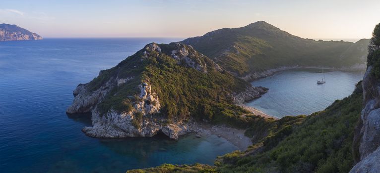 Panoramic view of beautiful famous double beach Porto Timoniand bay in Afionas from the view point on the path. Sunset golden pink light, Corfu, Greece