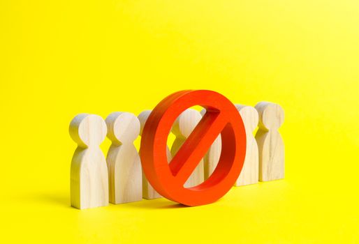 People figurines stand behind the red NO symbol on a yellow background. The concept of a ban on the expression of other opinions, suppression of dissent and freedom of speech. Genocide, repression.