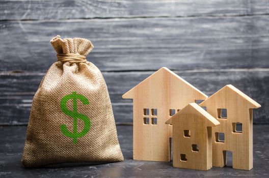 A bag with money and three houses. Concept of real estate acquisition and investment. Affordable cheap loan, mortgage. Taxes, rental income. Building houses. Municipal budget of the community.