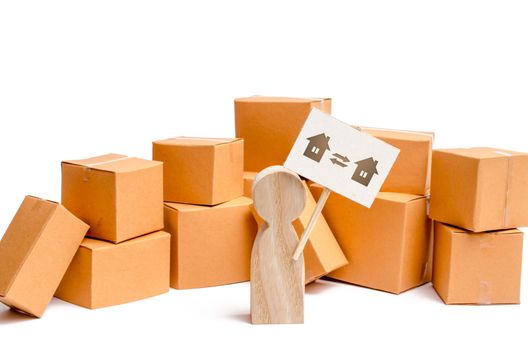 A wooden figurine of a person stands near a pile of boxes and raises the question of how to transport the goods from one house to another. The concept of moving to a new home, transportation companies