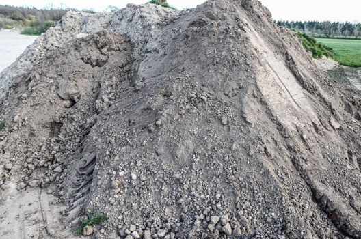 View into a gravel pit with piles of sand and some tire tracks