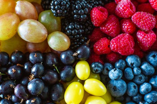 Mix of colored berries in a round plate divided by triangles. Stylish layout of useful vitamins of summer berries.