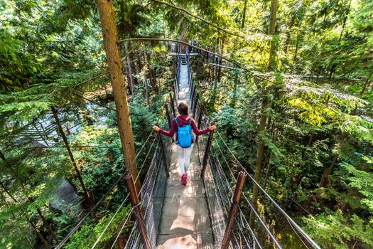 Canada travel tourist woman walking in famous attraction Capilano Suspension Bridge in North Vancouver, British Columbia, canadian vacation destination for tourism