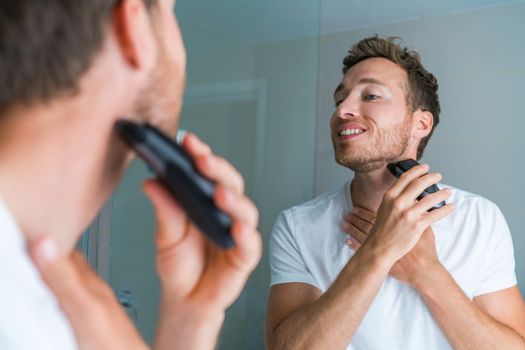 Young man shaving neck and jawline in the morning using electric shaver / clipper. Morning routine modern lifestyle. Male beauty 30s model