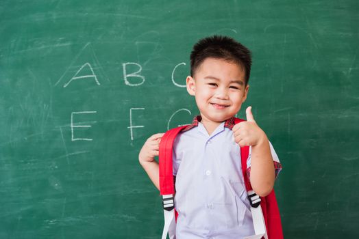 Child boy kindergarten in student uniform with school bag and bo