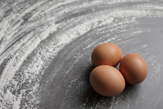 Three Chicken egg and flour on grey background table. Eggs