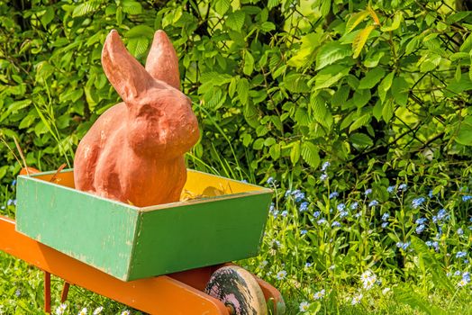 Easter bunny in an old barrow in a garden 
