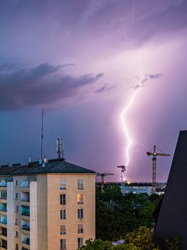 Violent summer thunderstorm with enormous lightning over the Wienerberg City in Vienna with construction cranes on the right side of the picture