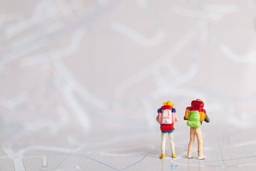 Miniature people : Traveler with backpack walking on map