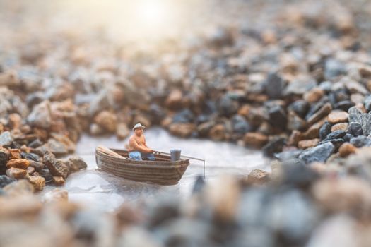 Miniature fishermen are fishing by boat 
