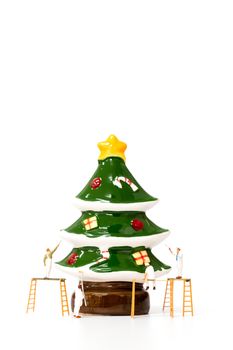 Miniature worker team painting Christmas prop on white backgroun