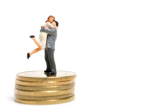 Miniature people: Couple hugging standing on stack of coin