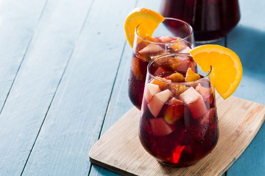 Red wine sangria in glass on blue wooden table.