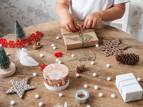 Child wrapped Christmas presents in craft paper with white fluff