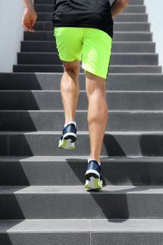 Runner man athlete running up the stairs on hiit high intensity interval training city run. Jogging jogger climbing staircase sprinting with speed. Urban active lifestyle. Closeup of legs and shoes.