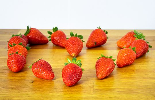 Fresh red strawberries shaped into a heart on a woody background