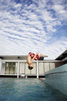 Boy (7-9) jumping into pool side view