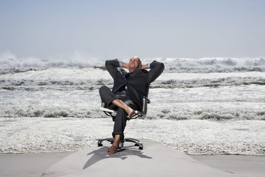 Senior business man sitting on office chair on beach