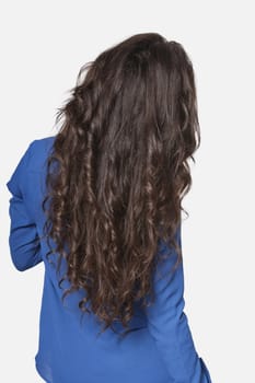 Rear view of a young woman with long brunette hair over gray background