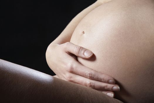 Pregnant woman holding abdomen mid section side view studio shot