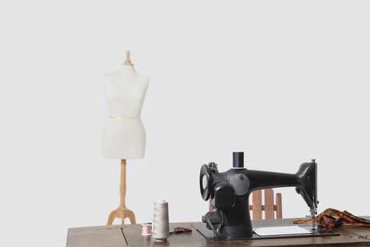 Mannequin and sewing machine with threads over gray background