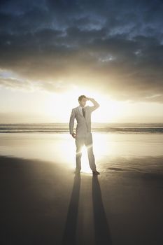 Business man standing on beach against sunset