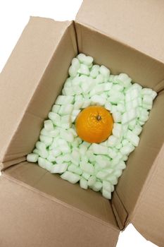 Open cardboard box with packing peanuts and orange in it