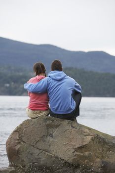 Couple embracing on rock by ocean