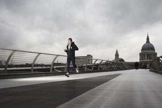 Young male runner on the Millenium Bridge with St Paul's in the background