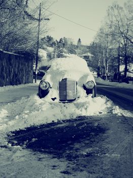 Old fashioned car buried under snow