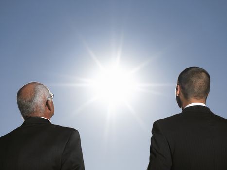 Businessmen looking at the sun head and shoulders back view