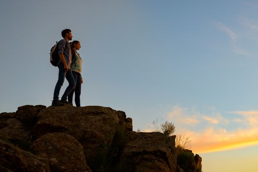 Couple of Young Travelers Standing on the Top of the Rock at Summer Sunset. Family Travel and Adventure Concept