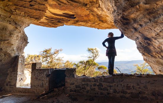 Woman looking out to mountain views from a large cave