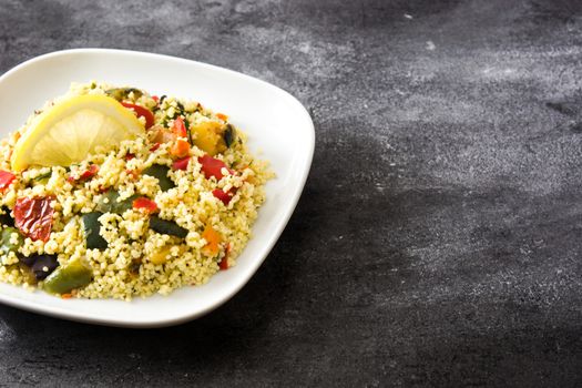Couscous with vegetables on black background