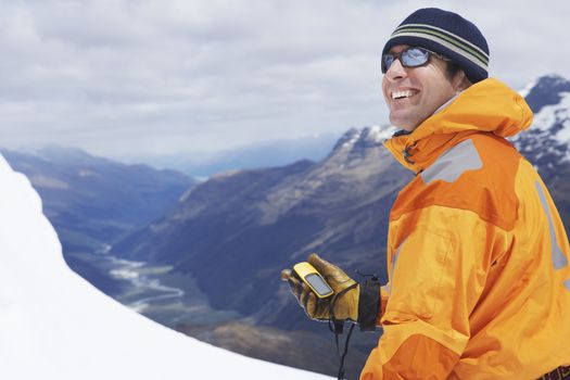 Mountain climber holding compass in snowy mountains