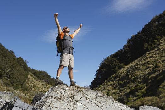 Hiker with arms outstretched on rock in river