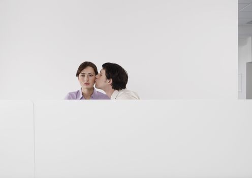 Man kissing female colleagues cheek in office cubicle