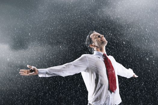 Businessman standing arms spread facing incoming rain