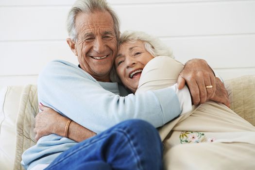 Senior couple cuddling on couch half length