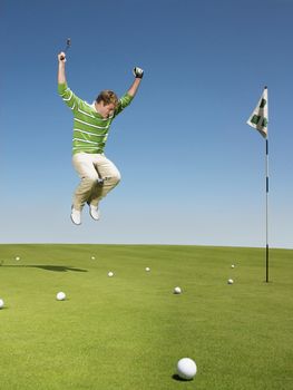Young male golfer jumping on green
