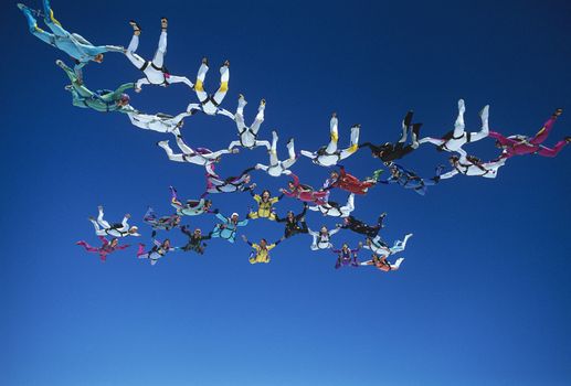 Skydivers holding hands in net formation in blue sky