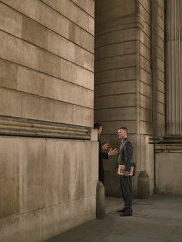 Two businessmen talking at entrance of monumental building