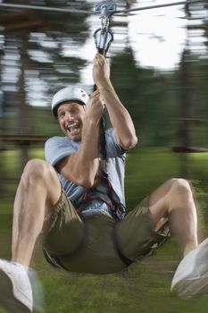 Portrait of Man riding zip-line in forest