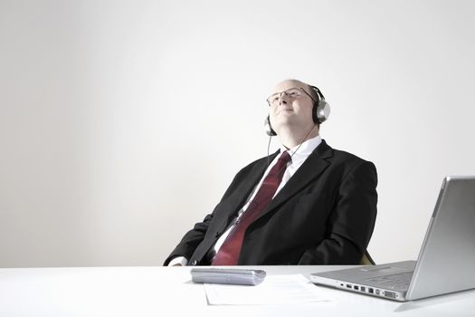 Businessman with earphones relaxing at desk