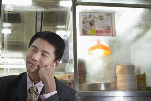 Young business man listening to mp3 player in bar