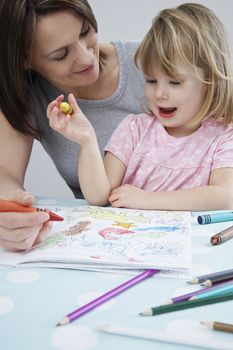 Mother helping daughter with colouring in book